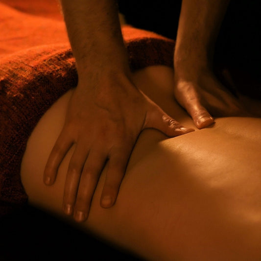 Person receiving a massage with hands on a back in a dimly lit setting